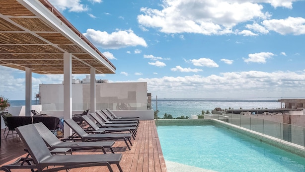 A rooftop pool with lounge chairs and a view of the ocean. - Oceanview Rooftop Pool, Gym & 1 Block to 5th Ave (Playa del Carmen)