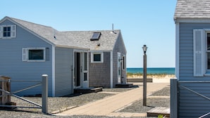 Une propriété située en bord de mer, comprenant une maison dotée d’un petit porche, d’une porte et d’une fenêtre.