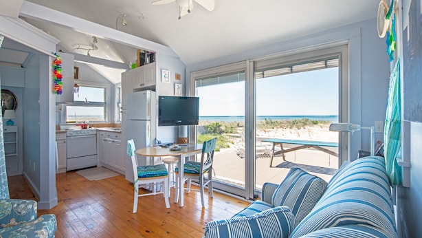 Une chambre située en bord de mer, dotée d’une cuisine, d’un coin repas et d’une grande fenêtre donnant sur la plage.