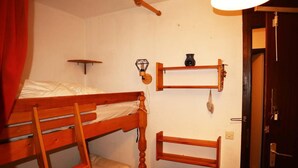 Kerrossänky, jossa on tikkaat, pieni hylly maljakolla ja lattialla oleva patteri.