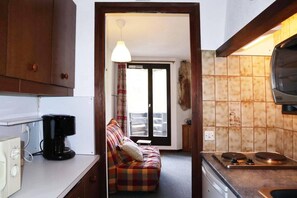 A compact kitchen with a coffee maker, a stove, and a dining area with a sofa. - 50m from ski slopes, 3rd floor, balcony, 26m², Les Orres (Les Orres)