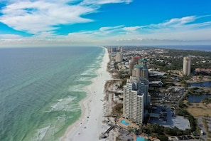 A coastal cityscape with a beach, high-rise buildings, and a marina.
