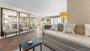 Un salón amplio con un sofá grande, una mesa de centro y vistas al exterior a través de amplios ventanales.