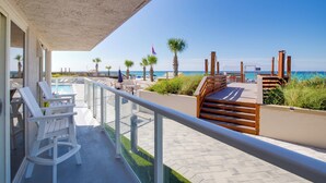 Un balcón con piscina, terraza de madera y vista al mar.