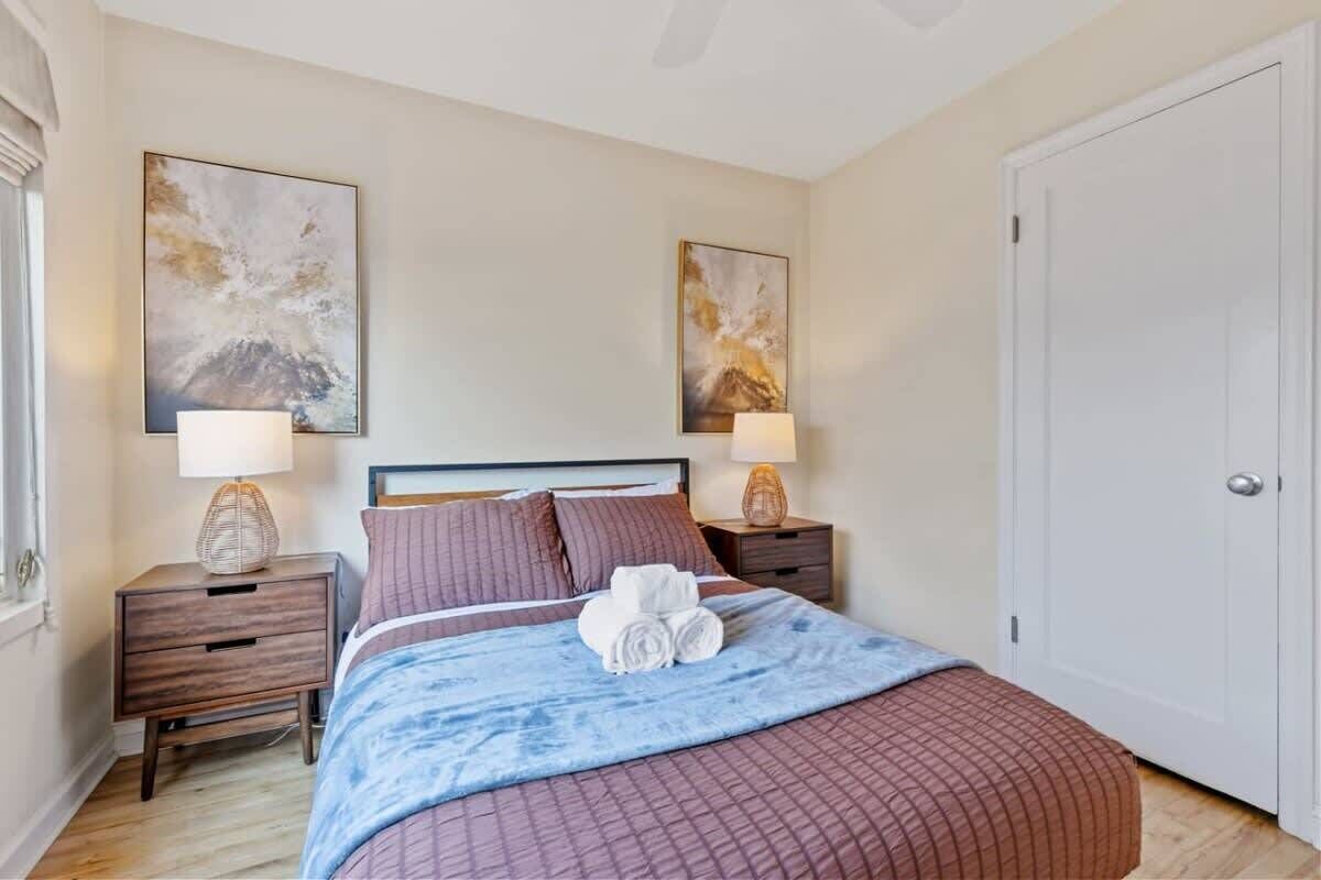 A neatly arranged bedroom with a bed, two bedside tables, a nightstand, and two wall-mounted lamps.