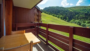 Een houten chalet met een balkon met uitzicht op een groene vallei.