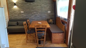 Une pièce chaleureuse avec une table en bois, deux chaises, un banc, un canapé et un mur en pierre agrémenté d’un luminaire.