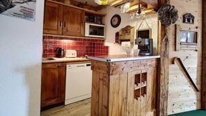 Een rustieke keuken met houten kasten, een rode tegelachterwand, een ingebouwde magnetron en een keukeneiland met een spoelbak.