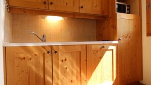 Une cuisine avec des meubles en bois, un dosseret carrelé et un évier en acier inoxydable.
