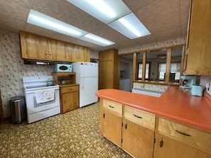A kitchen with wooden cabinets, a white refrigerator, a stove, and a microwave.