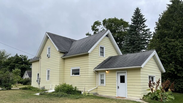 A two-story house with a gabled roof and a front door.
