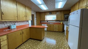 A kitchen with wooden cabinets, a central island, a sink, and a refrigerator.