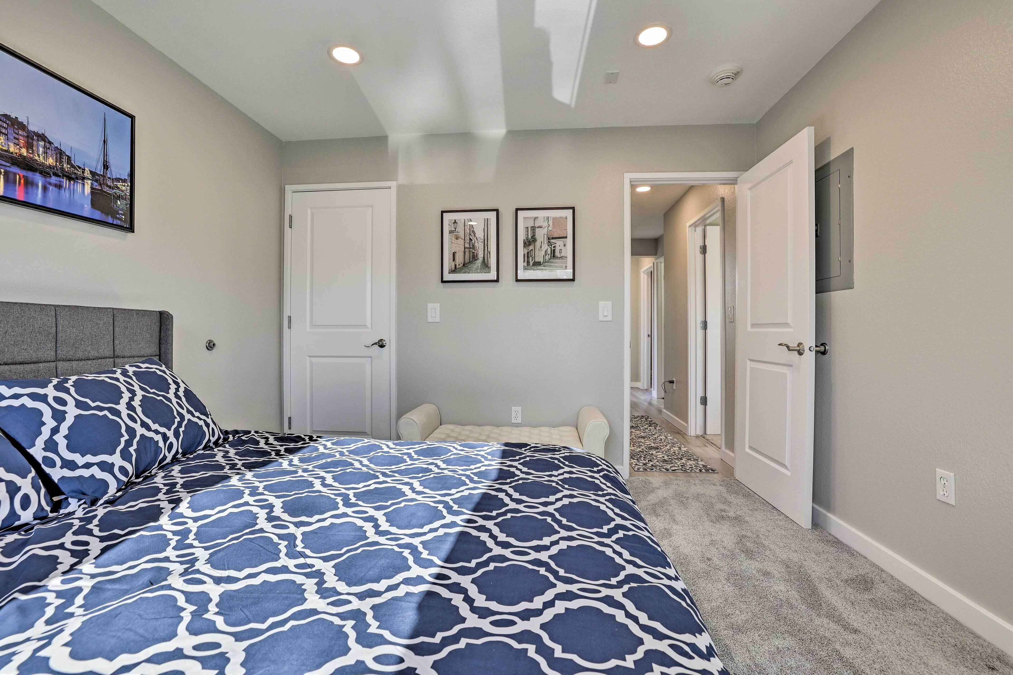 A bedroom with a patterned bedspread, a headboard, and two framed pictures on the wall.