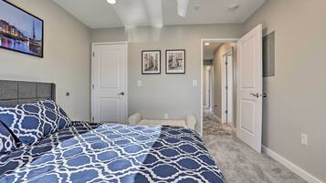 A bedroom with a patterned bedspread, a headboard, and two framed pictures on the wall.