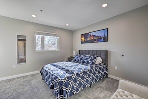 Un dormitorio con una cama grande, una ventana, una mesita de noche y un cuadro colgado en la pared.