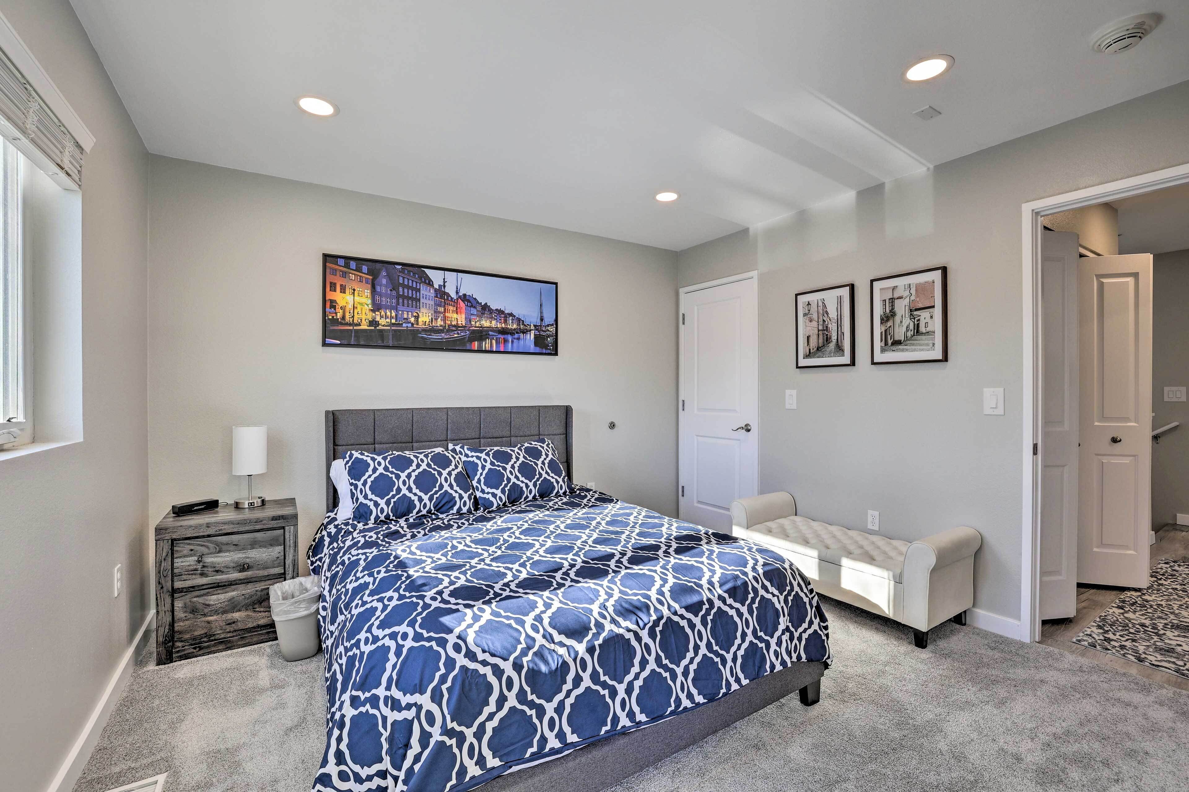 A bedroom with a bed, a nightstand, a lamp, a chair, and a door.