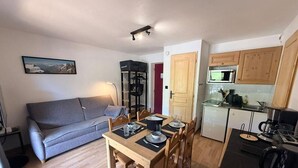 A compact living space with a dining table, chairs, a sofa, a kitchenette, and a mounted television. - 10m from resort center, 1st floor, terrace, tv, ski locker, 26m², Montgenèvre (Montgenèvre)