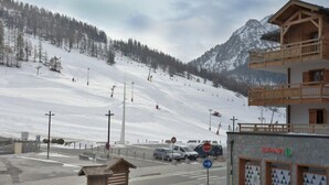 A ski resort with a wooden building, a ski lift, and a snowy mountain backdrop. - 10m from resort center, 1st floor, terrace, tv, ski locker, 26m², Montgenèvre (Montgenèvre)