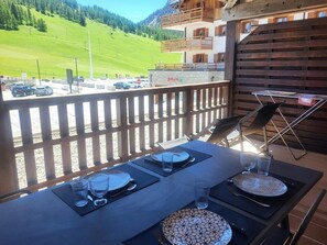 A dining table set outdoors with a view of a parking area and mountains.
