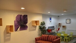 A cozy living area with a sofa, chairs, a small table, and a large flower painting on the wall. - 10m from resort center, 1st floor, terrace, tv, ski locker, 26m², Montgenèvre (Montgenèvre)