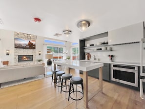 A modern kitchen with a central island, bar stools, a fireplace, and a dining area with a view. - Penthouse Suite in Canyons Village•2 Kitchens•Private Hot Tub•Resort Amenities (Park City)