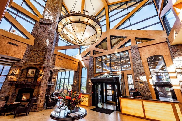 A spacious lobby with a stone fireplace, large windows, and a modern chandelier.