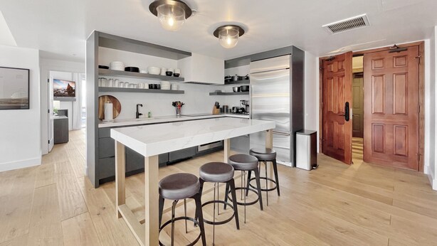 Una cocina moderna con una isla central, taburetes de bar y electrodomésticos integrados.