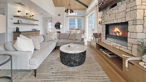 Una sala de estar moderna con chimenea de piedra, un sofá grande y una mesa de centro redonda.