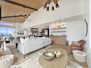 A spacious living area with a large sofa, a dining table, and a kitchen in the background.
