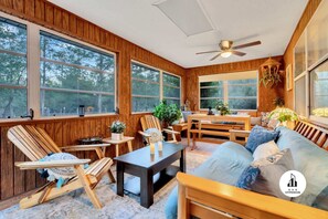 Relax in a warm, inviting space with a comfortable seating area and large windows offering views of the surrounding trees.
