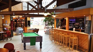 A billiards table, bar area, and seating in a well-lit indoor space with wooden beams and tiled flooring. - La Petite Fecht (Munster)