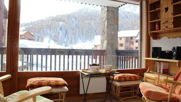 A cozy room with a wooden bench, a small table with cups and a teapot, and a view of a snowy mountain landscape. - 200m from ski slopes, 2nd floor, tv, 55m², Vars (Vars)