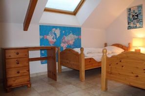 Un dormitorio con tragaluz, una cama de madera, un aparador de madera y un mapa del mundo en la pared.
