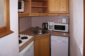 A compact kitchen with a stove, sink, microwave, and dishwasher.