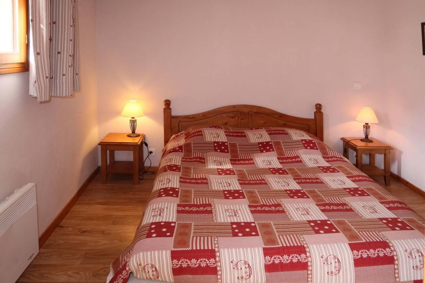 A bedroom with a wooden bed, two bedside tables with lamps, and a patterned bedspread.