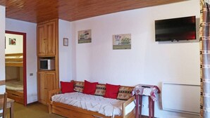 A cozy room with a wooden bunk bed, a single bed with patterned pillows, a small table with a cloth, and a wall-mounted TV. - 250m from shops, 3rd floor, view valley, balcony, 30m², Les Orres (Les Orres)