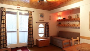A cozy room with a wooden ceiling, a sofa, a small table, and a window with curtains. - 250m from shops, 3rd floor, view valley, balcony, 30m², Les Orres (Les Orres)