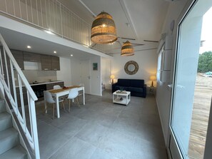 A modern interior with a dining area, sofa, and a staircase.
