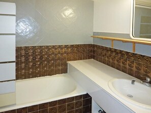 A bathroom with two sinks, a mirror, and patterned tiles.