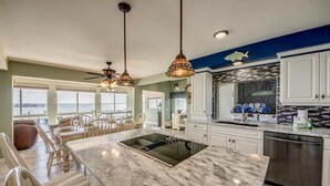 A kitchen with a large island, white cabinets, and a view to the outside. - 21431 Widgeon Bayfront Pool Home near the Beach (Fort Myers Beach)
