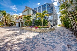 A modern building with a glass facade, surrounded by a paved area with palm trees and a landscaped garden.