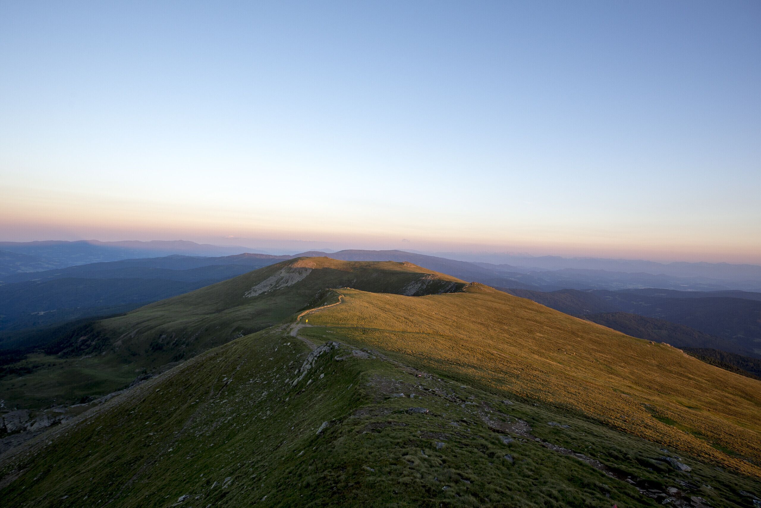 Une vue panoramique d’un paysage montagneux avec un sentier sinueux.