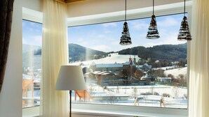 Ein Essbereich mit einem Tisch für zwei Personen, einem Fenster mit Blick auf eine verschneite Landschaft und hängenden Pendelleuchten.