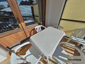 Un balcon avec une table et des chaises, donnant sur un paysage enneigé.