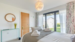 A bedroom with a bed, a bedside table, a mirror, a door, and a view of the outside. - 3 Bed in Westward Ho! (oc-dreck) (Northam)