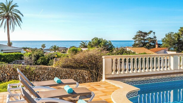 A poolside area with lounge chairs and a view of the sea. - Casa del Sol - Six Bedroom Villa, Sleeps 7 (Binibeca)