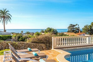 Un espace aménagé au bord de la piscine, avec des chaises longues et une vue sur la mer.