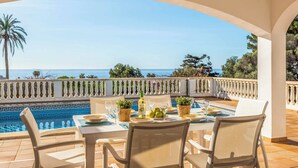 A dining area with a table set for two, overlooking a pool and the sea. - Casa del Sol - Six Bedroom Villa, Sleeps 7 (Binibeca)