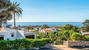 A coastal residential area with white buildings, palm trees, and a view of the sea. - Casa del Sol - Six Bedroom Villa, Sleeps 7 (Binibeca)