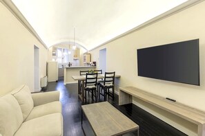 A modern living room with a sofa, a coffee table, and a TV mounted on the wall.